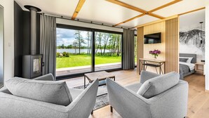 Ein modernes Wohnzimmer mit einem großen Schiebeglasfenster zum Garten, einem Kamin und einem Essbereich mit Tisch und Stühlen.
