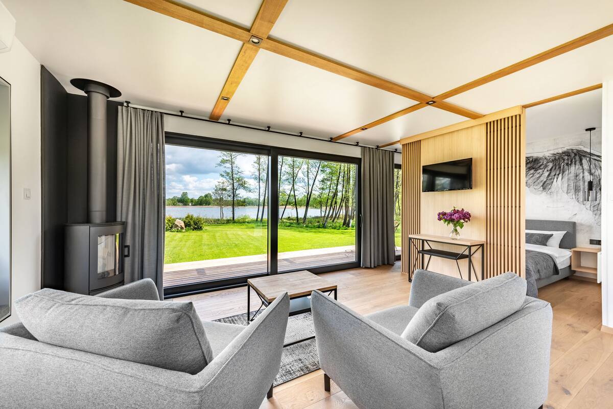 A modern living room with a large sliding glass door leading to a garden, a fireplace, and a dining area with a table and chairs.