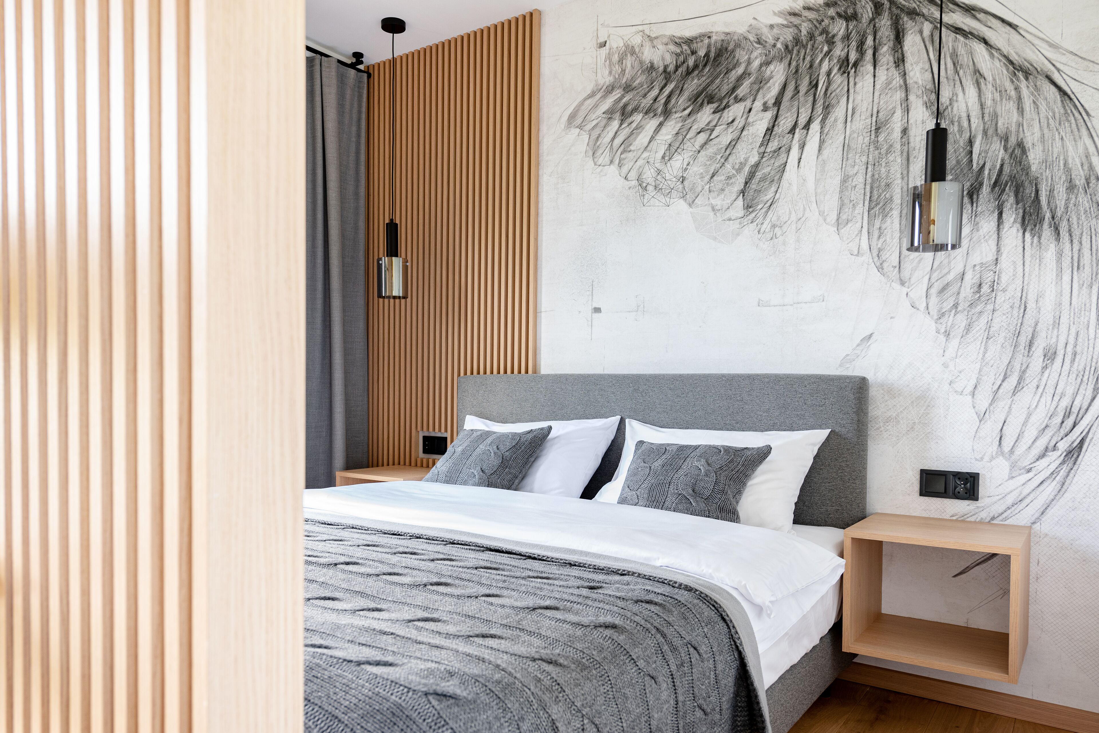 Un dormitorio moderno con cabecera gris, mesita de noche de madera y un cuadro abstracto grande en la pared.