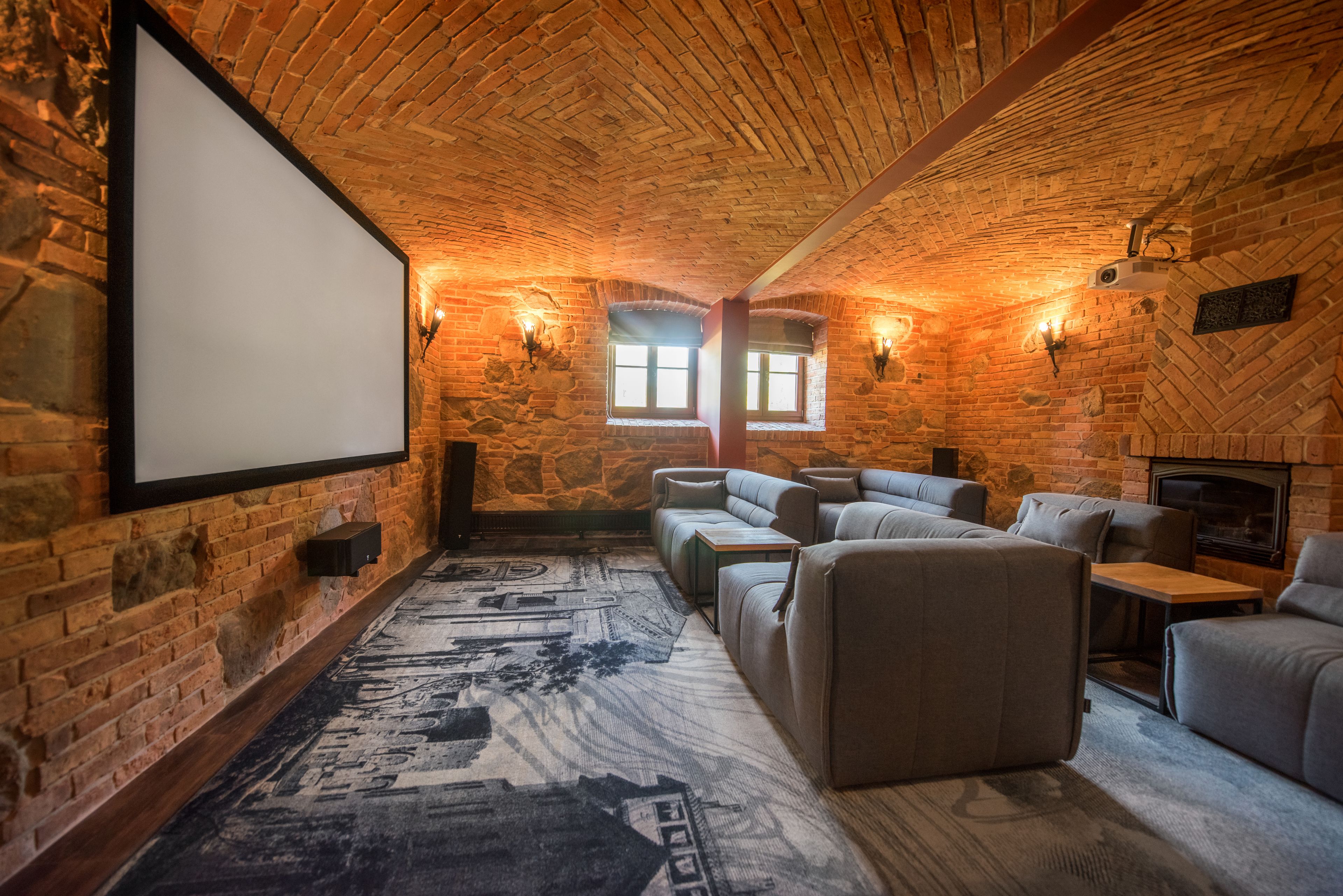 A cozy room with a brick ceiling, a large screen, and comfortable seating.