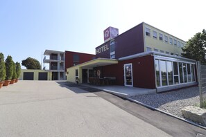 Un hotel moderno con techo plano, acceso cubierto y un área de estar al aire libre.