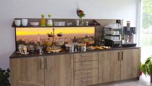 A breakfast buffet with various food items, a coffee machine, and a decorative wall piece. - IQ Hotel (Langenau)