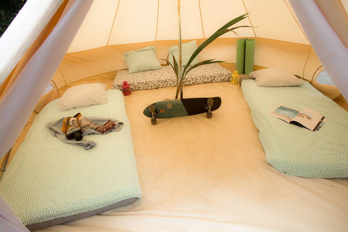 A tent with two sleeping areas, each with a pillow and a blanket. A skateboard is placed in the center.