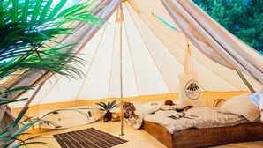 Una tienda acogedora con una cama, una mesita y una planta en maceta.