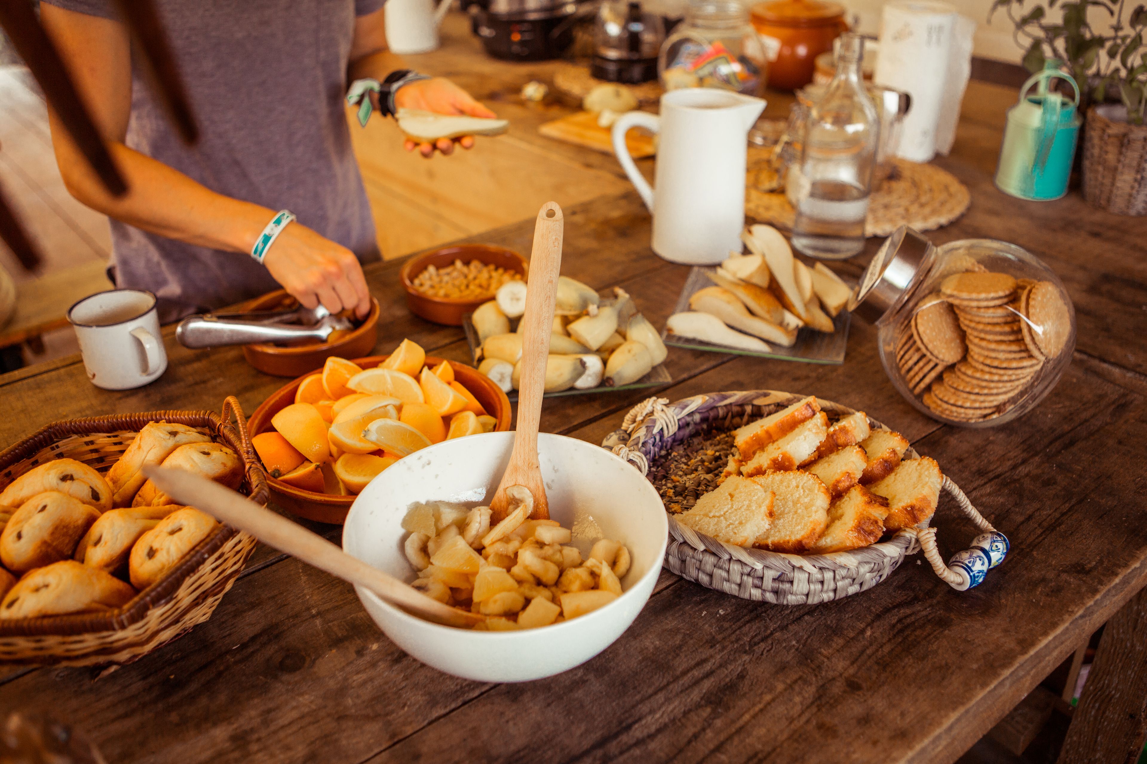 Una mesa de madera con diversos alimentos y utensilios, incluyendo cuencos, cestas y una jarra.