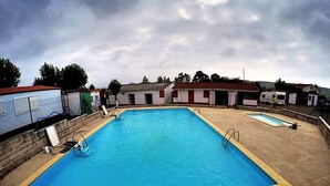 Una piscina rectangular con solárium alicatado y una piscina pequeña contigua.