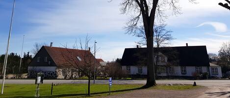 A rural street with two houses, one with a stone facade and the other with a white exterior.