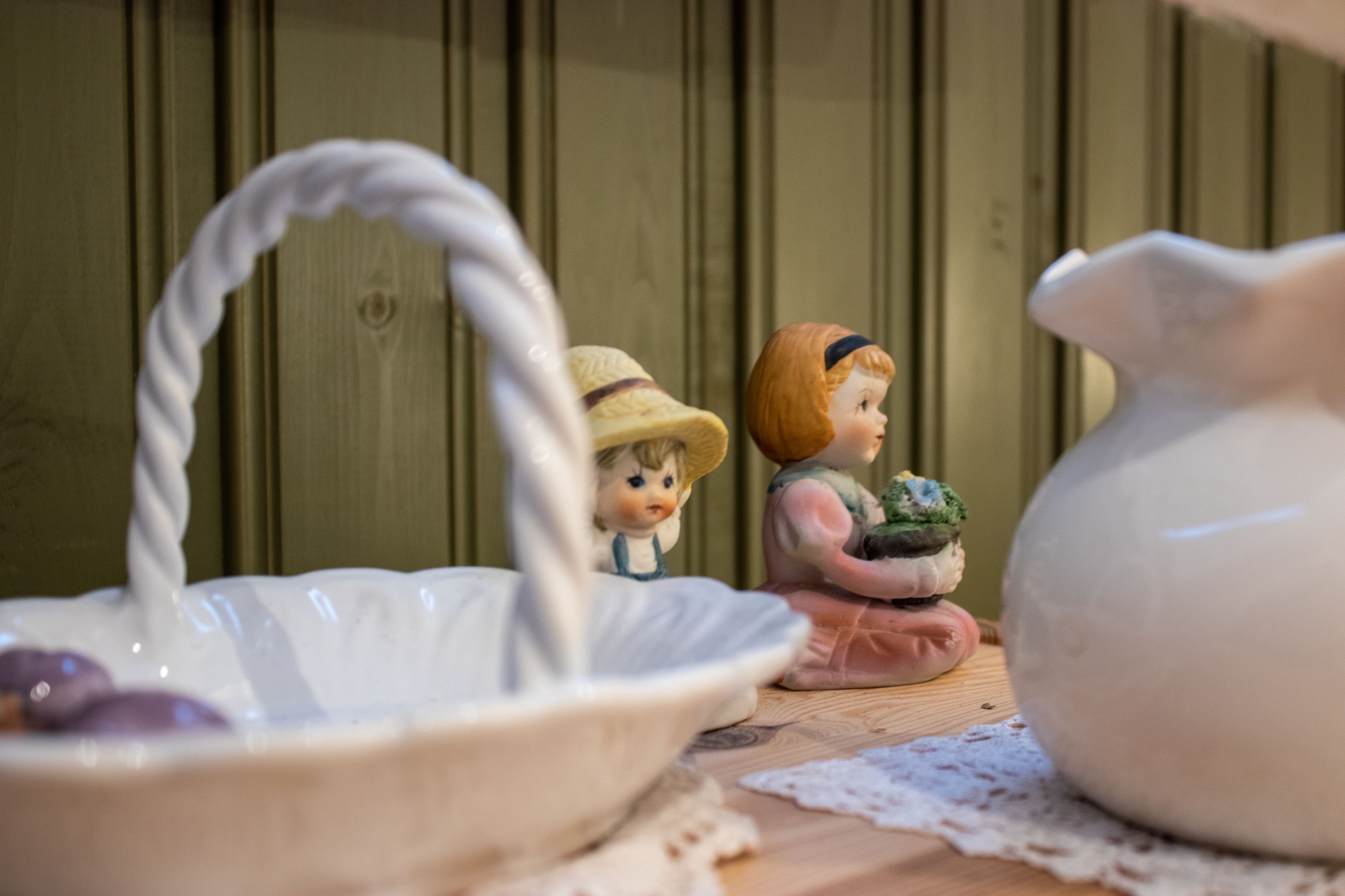 A ceramic jug, a ceramic bowl, and a figurine on a wooden surface.