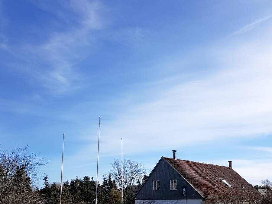 Una casa con facciata in pietra, tetto spiovente e cielo azzurro intenso.
