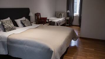 Una habitación de hotel con una cama grande, una silla, una mesita y un ventanal con cortinas.