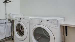 Une buanderie moderne équipée de deux machines à laver à chargement frontal, d’un étendoir et d’un lampadaire.