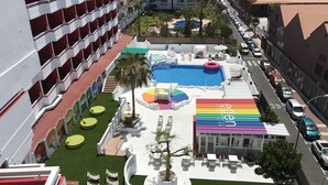 Un espace piscine sur le toit, avec un salon aux couleurs de l’arc-en-ciel, une piscine et des sièges extérieurs.