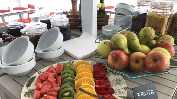 Une présentation de fruits comprenant des tranches de pastèque, de kiwi, d’orange et de fraises sur une assiette, ainsi que des fruits entiers comme des poires et des pommes.