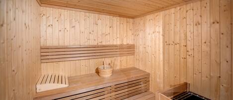 Una sauna in legno con panche e una seduta.