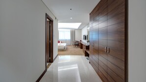 Une chambre d’hôtel moderne dotée d’une grande armoire, d’un lit, d’un bureau et offrant une vue sur la ville par la fenêtre.
