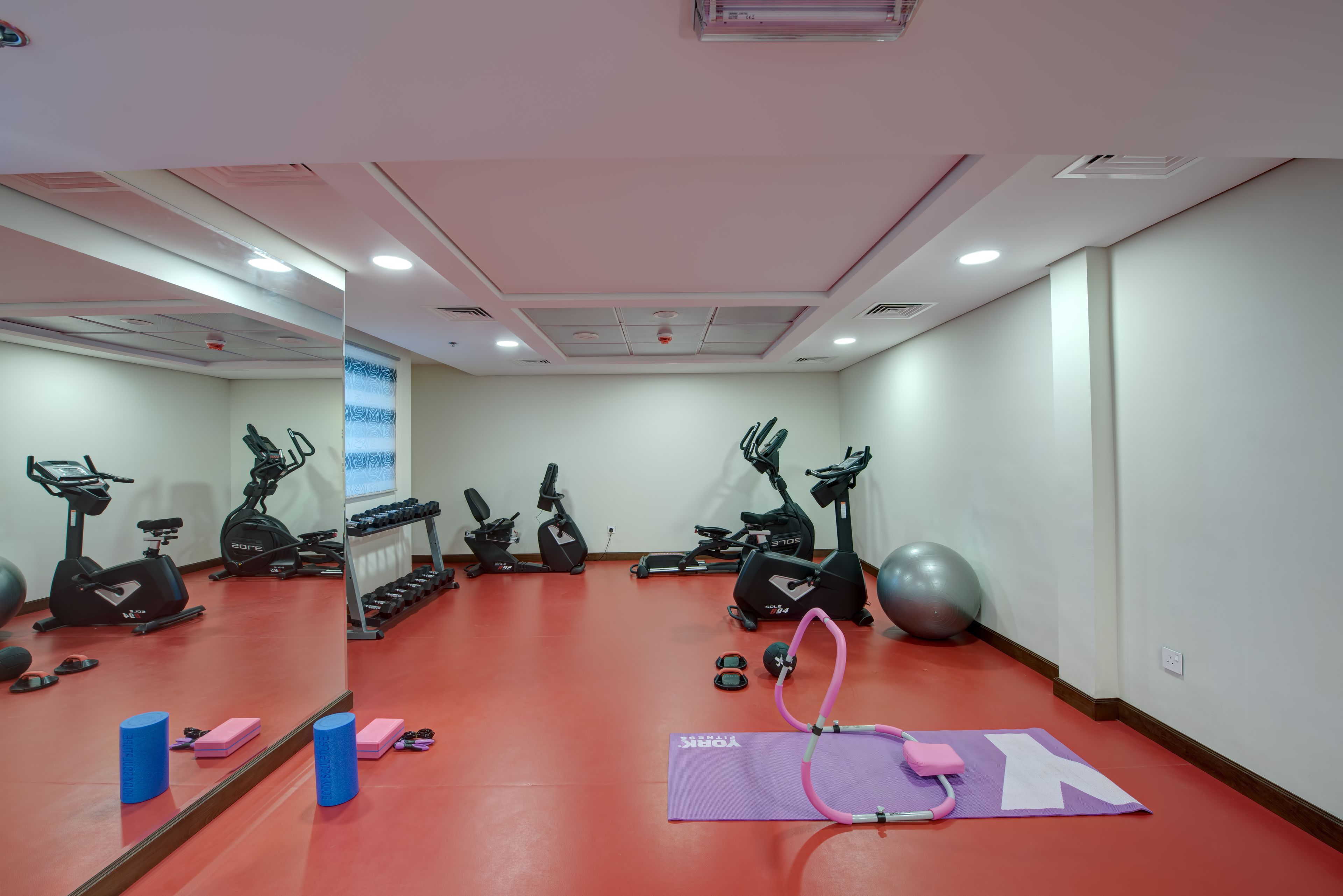 A gym with exercise equipment, a mirror, and a yoga mat.