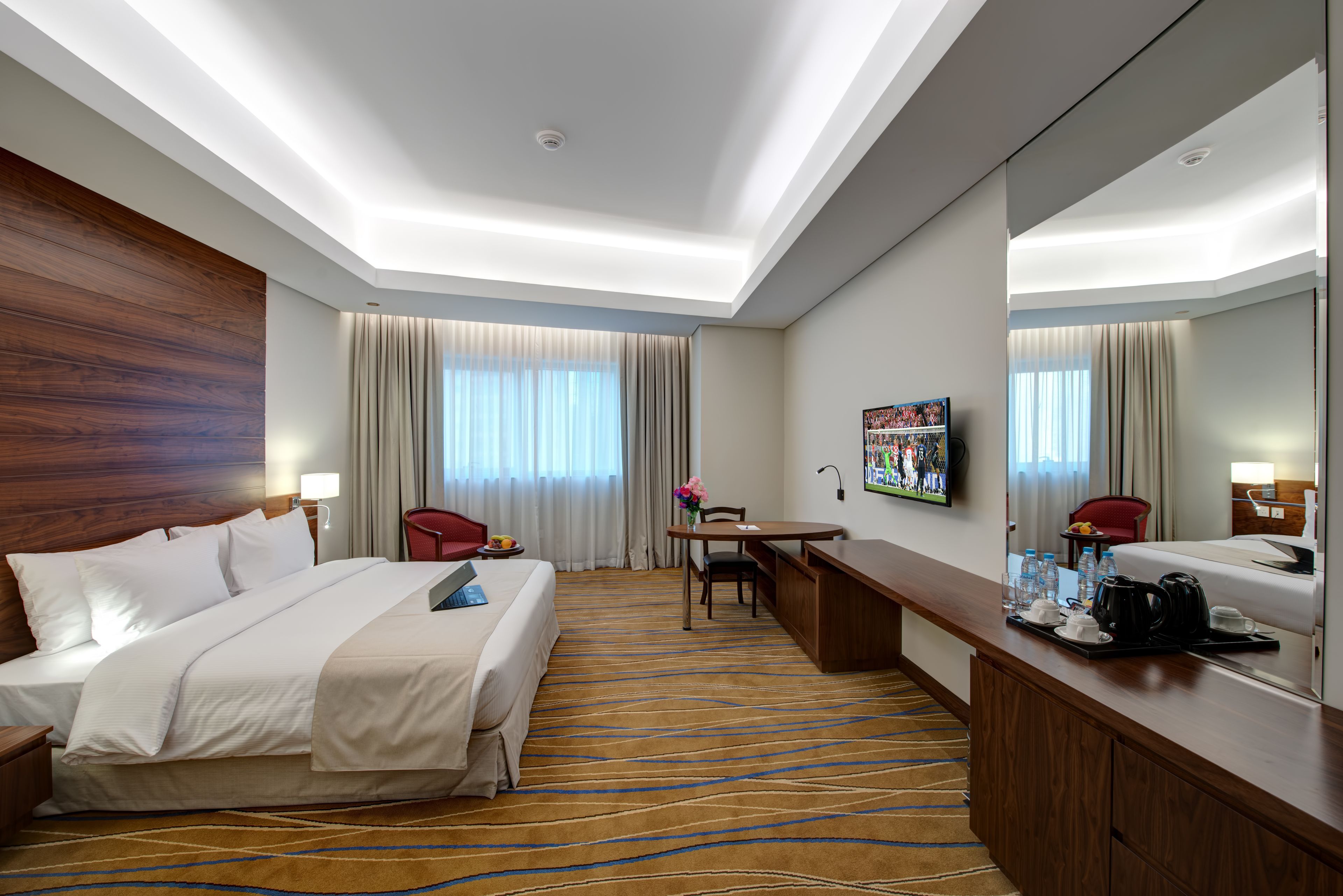 Een hotelkamer met een groot bed, een bureau, een stoel, een koffiezetapparaat en een televisie.