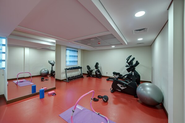 Un gimnasio con equipo de ejercicio, un espejo y suelo rojo.