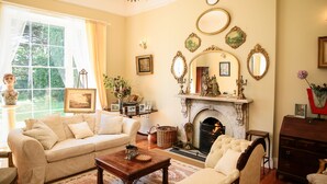 Un salón tradicional con chimenea, un sofá, una mesita de centro y una repisa de chimenea decorada con adornos.