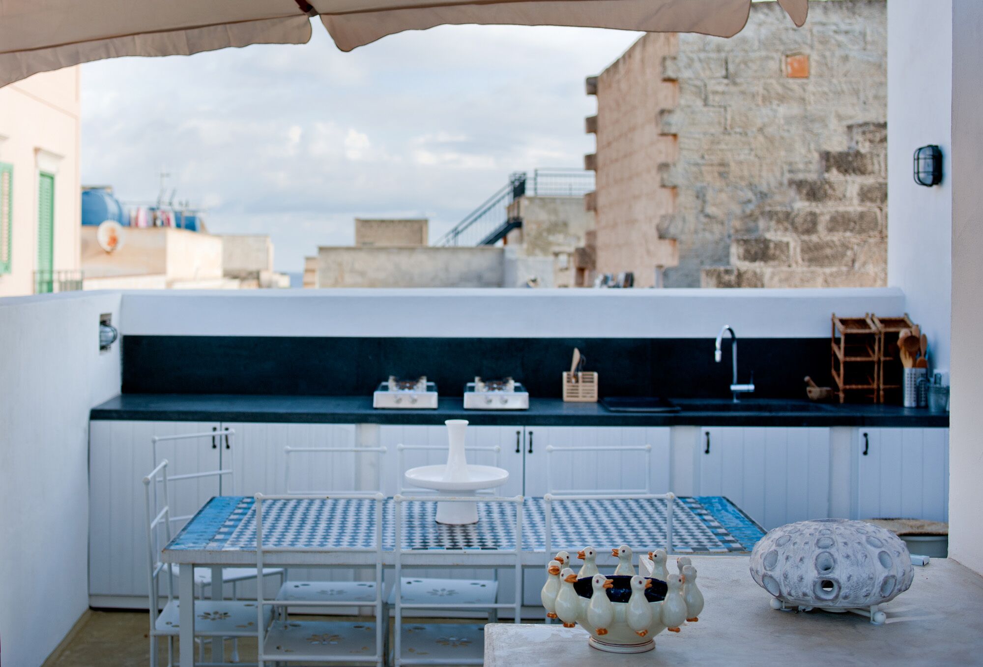 Una terraza en la azotea con mesa y sillas, un mueble blanco y vistas a la ciudad.