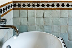 A bathroom with a white sink and a tiled backsplash featuring a geometric pattern. - La Casa dell'Arancio (Favignana)