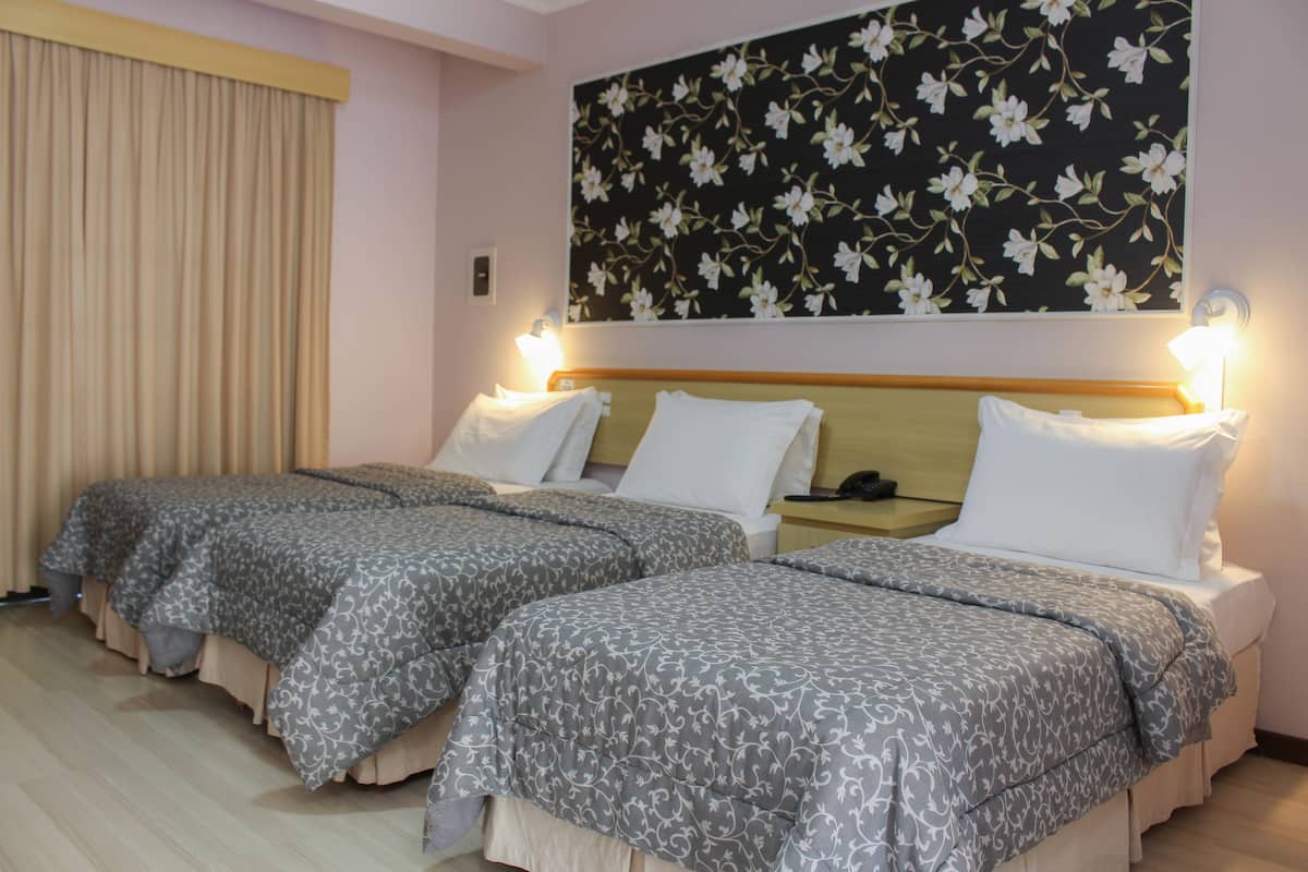 A hotel room with two beds, each with a headboard and bedside tables.