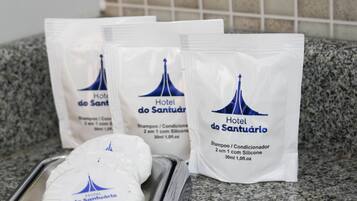 Tres botellas de champú y acondicionador del Hotel do Santuário sobre una encimera de cocina.