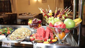 Un bufé con diversas opciones de comida, incluyendo ensaladas, frutas y un plato de sandía.