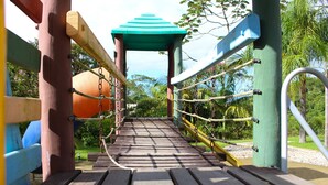 Un puente de madera con techo verde, que une dos zonas de juegos.