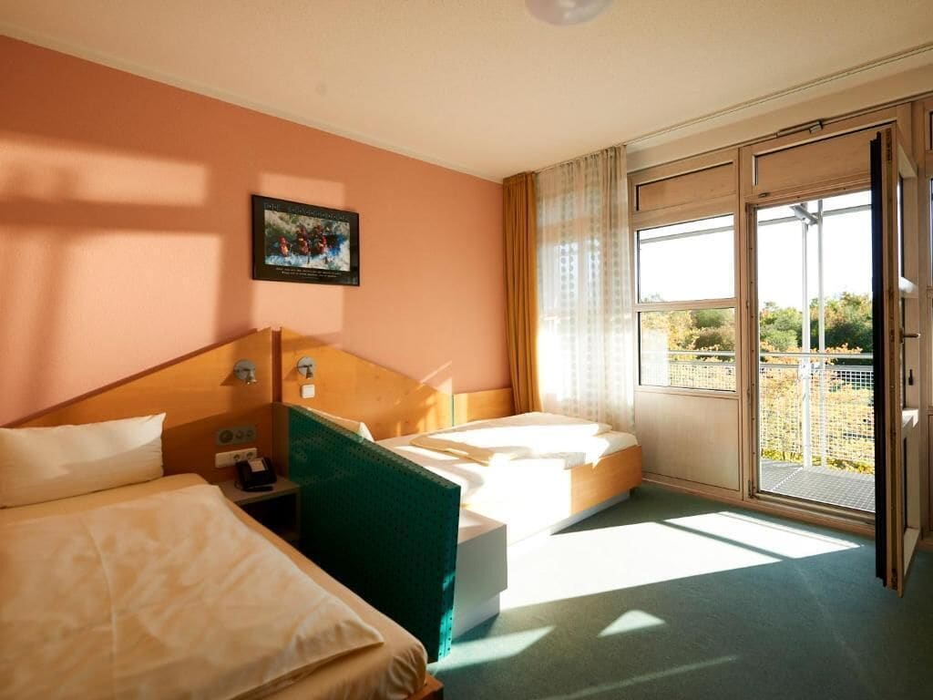 Una habitación de hotel con dos camas, un ventanal con vistas y un cuadro en la pared.