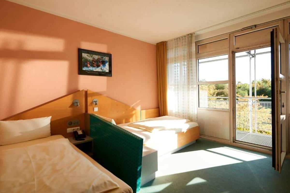 Una habitación de hotel con dos camas, un ventanal con vistas y un cuadro en la pared.