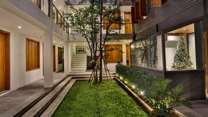 Um edifício com vários níveis e um pátio central com uma pequena árvore, degraus que levam a um andar superior e um pinheiro de Natal.