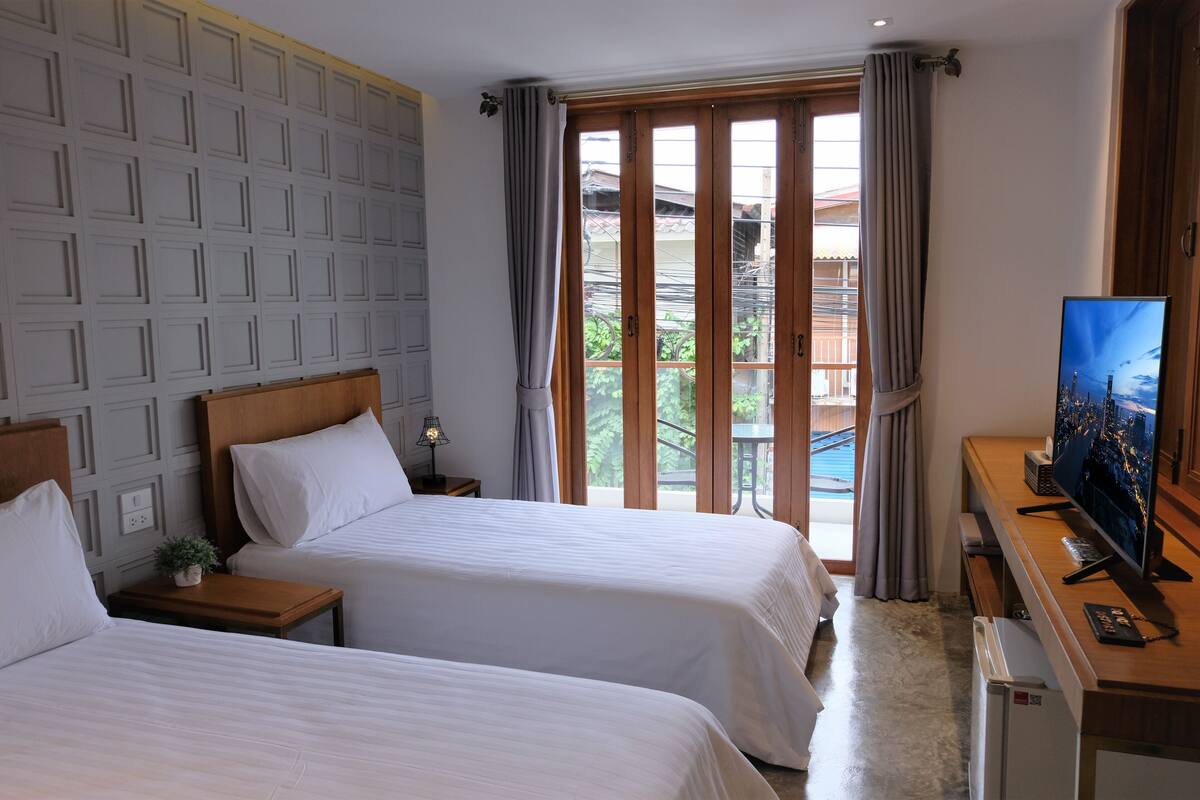 Une chambre d’hôtel avec deux lits, une télévision, un bureau et un balcon avec vue.
