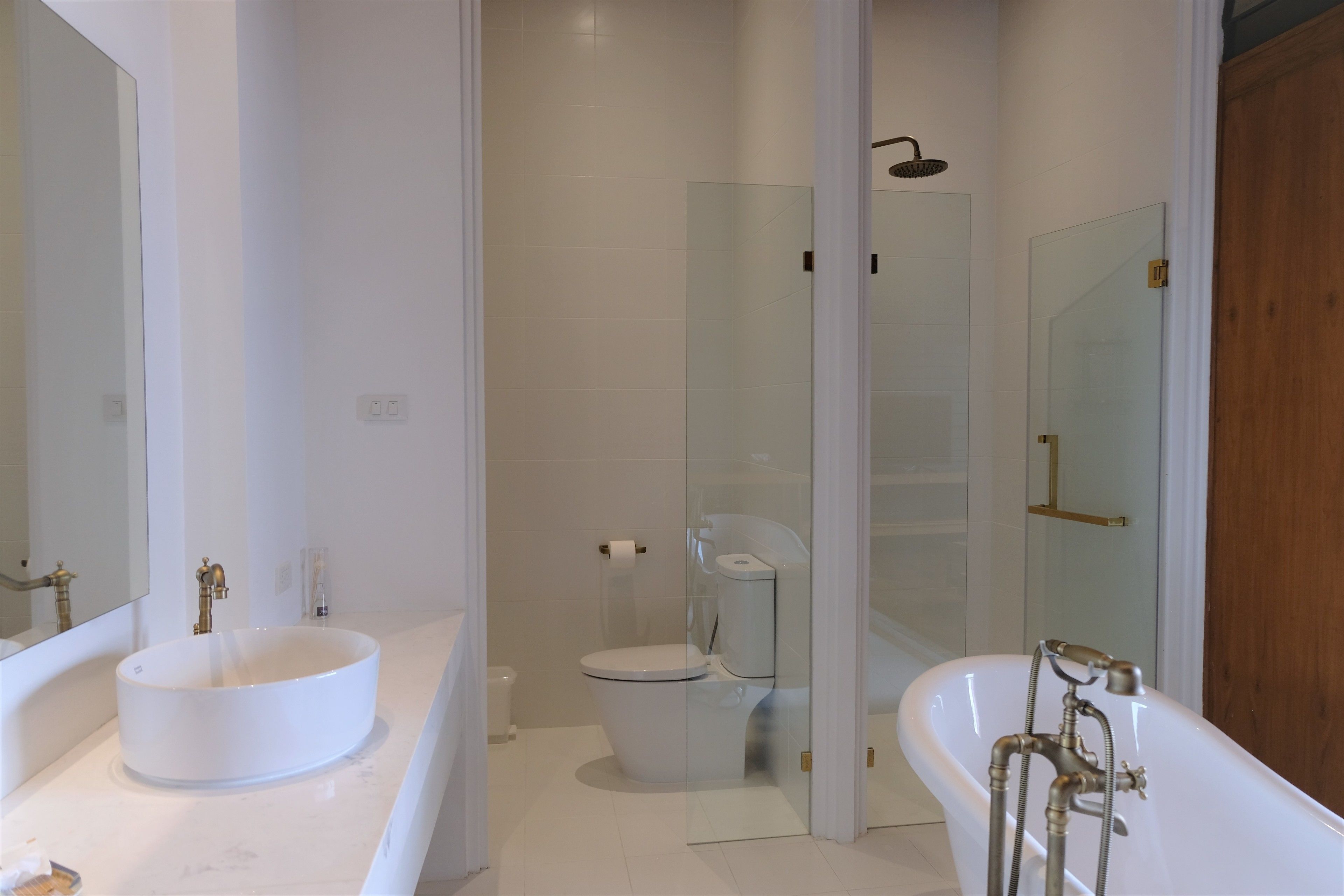 A modern bathroom with a large white sink, a bathtub, and a glass-enclosed shower.