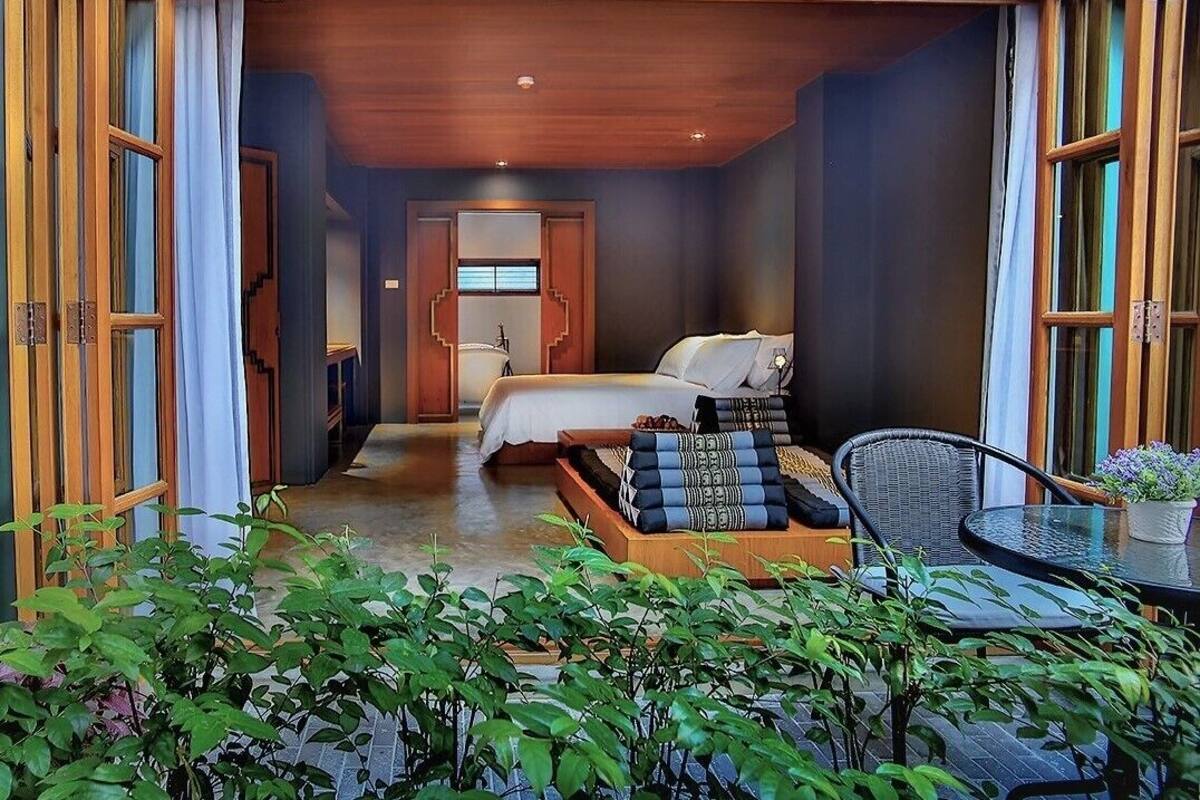 Une chambre d’hôtel de taille réduite, comprenant un lit, un petit coin salon et une vue sur l’extérieur.