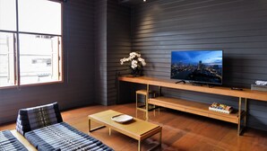 Uma sala de estar moderna com uma janela grande, uma TV de tela plana, um sofá, uma mesa de centro e um rack de madeira para TV.