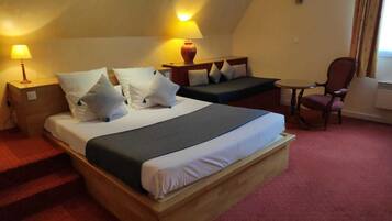 Een hotelkamer met een groot bed, een kleiner bed, een bureau, een stoel en een lamp.