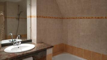 Une salle de bain équipée d’un lavabo, d’un miroir, d’une douche et d’une baignoire.
