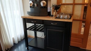 Uma kitchenette com uma máquina de café, um recipiente de vidro e um suporte para copos de vinho.