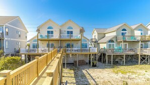 A beachfront property with multiple two-story houses, each featuring a balcony with outdoor furniture.