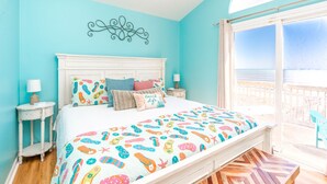 A bedroom with a large bed, a view of the sea, and a balcony.