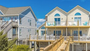A beachfront property with a two-story house featuring a balcony and a deck.