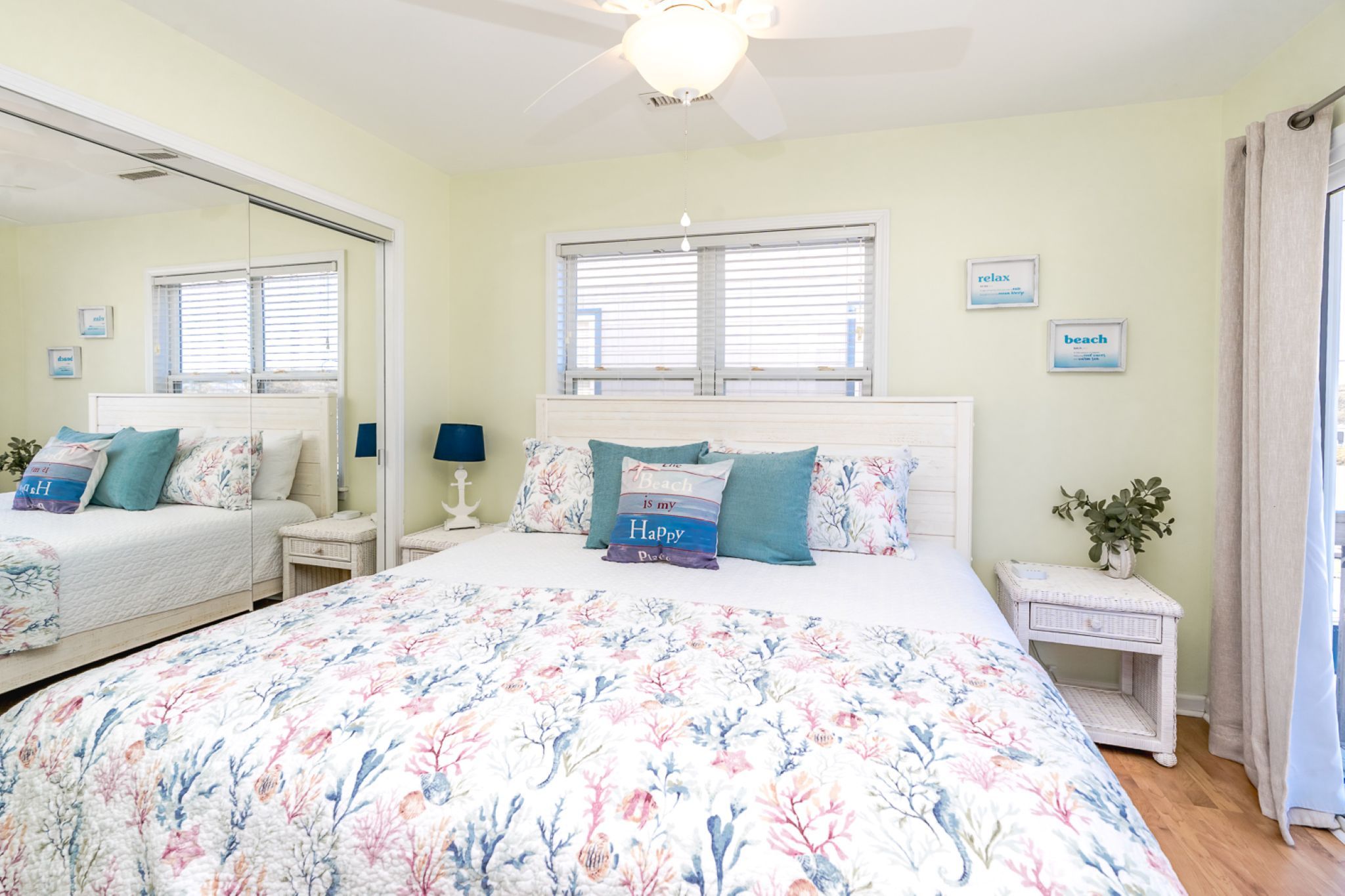 A bedroom with a large bed, a nightstand, a dresser, a mirror, and a ceiling fan.