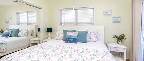 A bedroom with a large bed, a nightstand, a dresser, a mirror, and a ceiling fan.