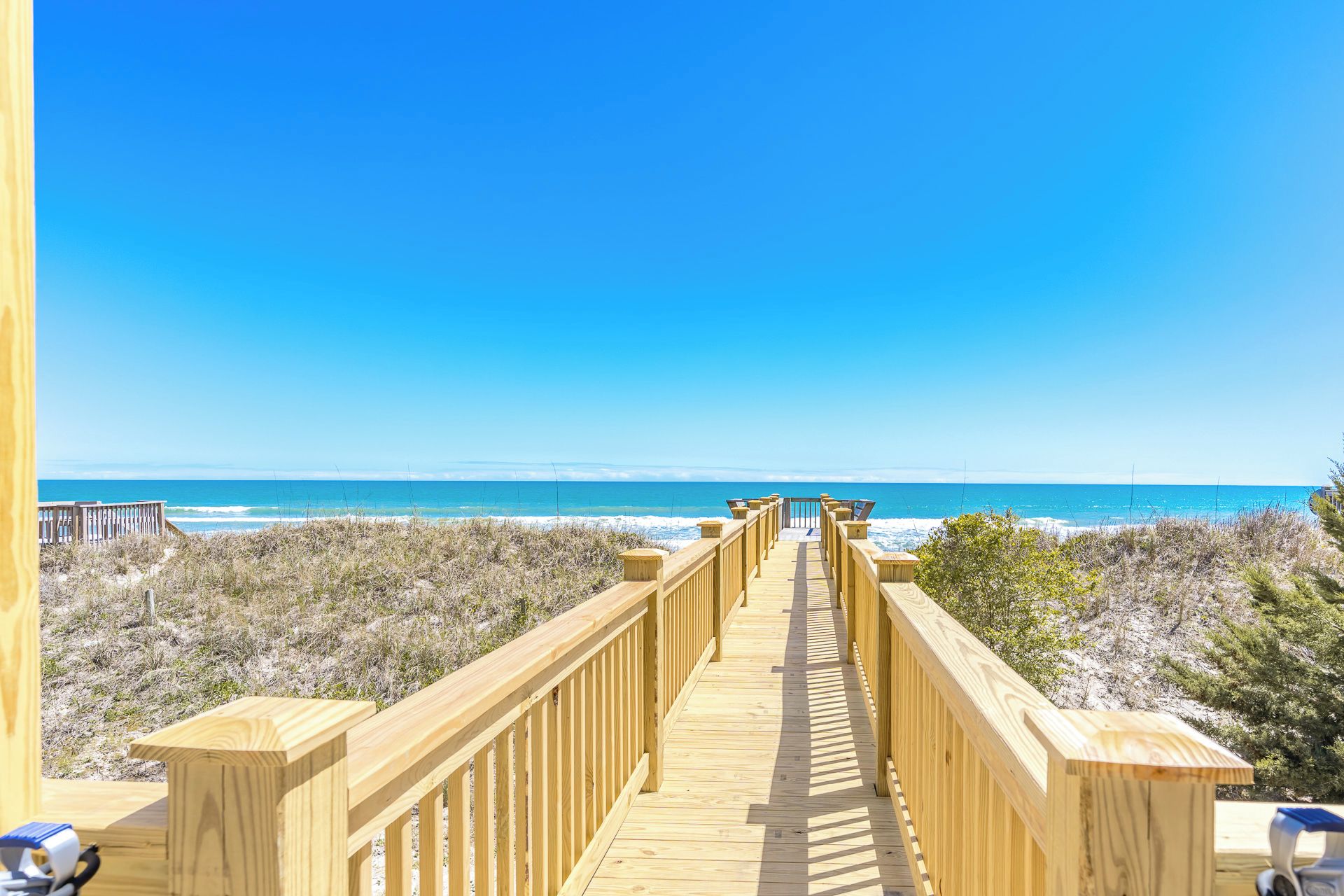 A wooden boardwalk leading to a beach with clear skies.