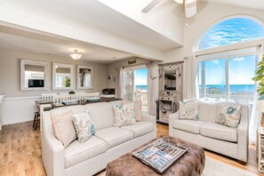 A spacious living room with a large window, a dining area, and a kitchen.