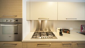 Eine Küche mit Edelstahlherd, einem Backofen, Holzschränken und einer weißen Arbeitsplatte.