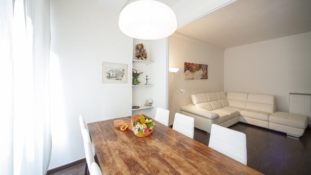 Ein modernes Wohnzimmer mit einem Holzespeisetisch, weißen Sofas und einem großen Gemälde an der Wand.