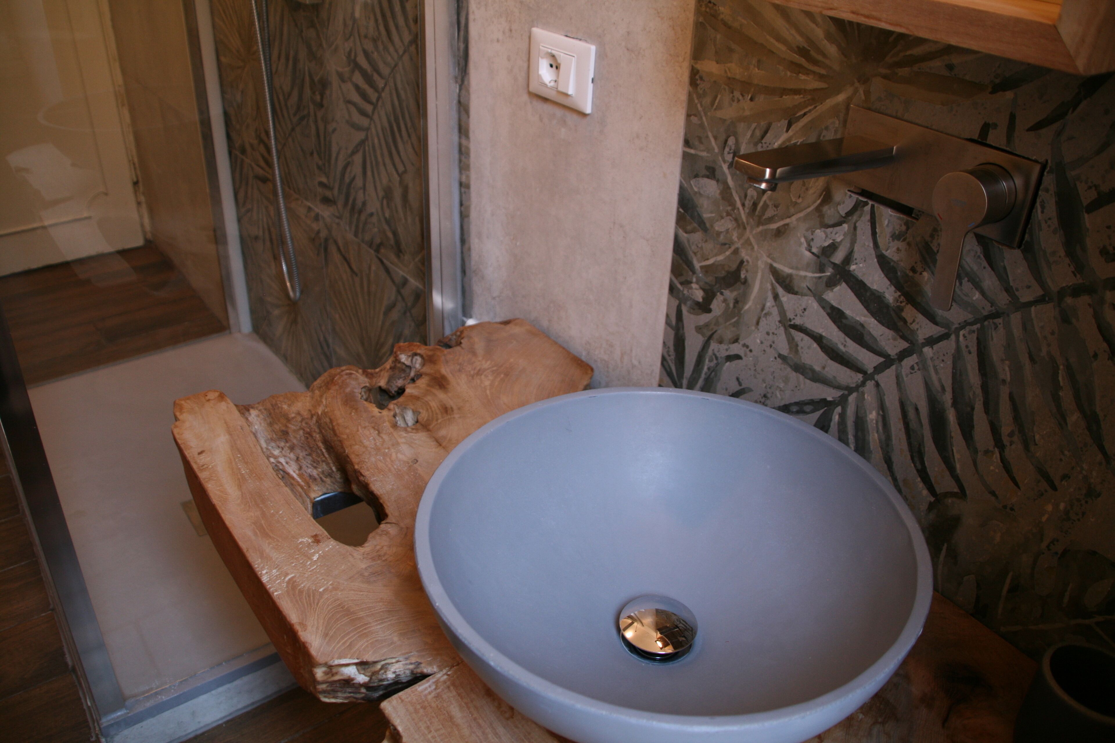 Een badkamer met een houten bankje, een groot wastafel en een douchegedeelte.
