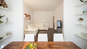 Ein modernes Wohnzimmer mit einer Eckcouch, einem Holzesstisch mit Stühlen und einem Fernseher auf einem Lowboard.